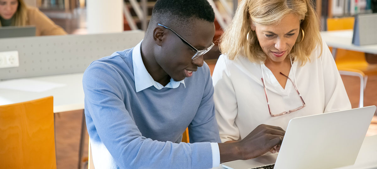 man and woman sharing a laptop in a discussion in the office