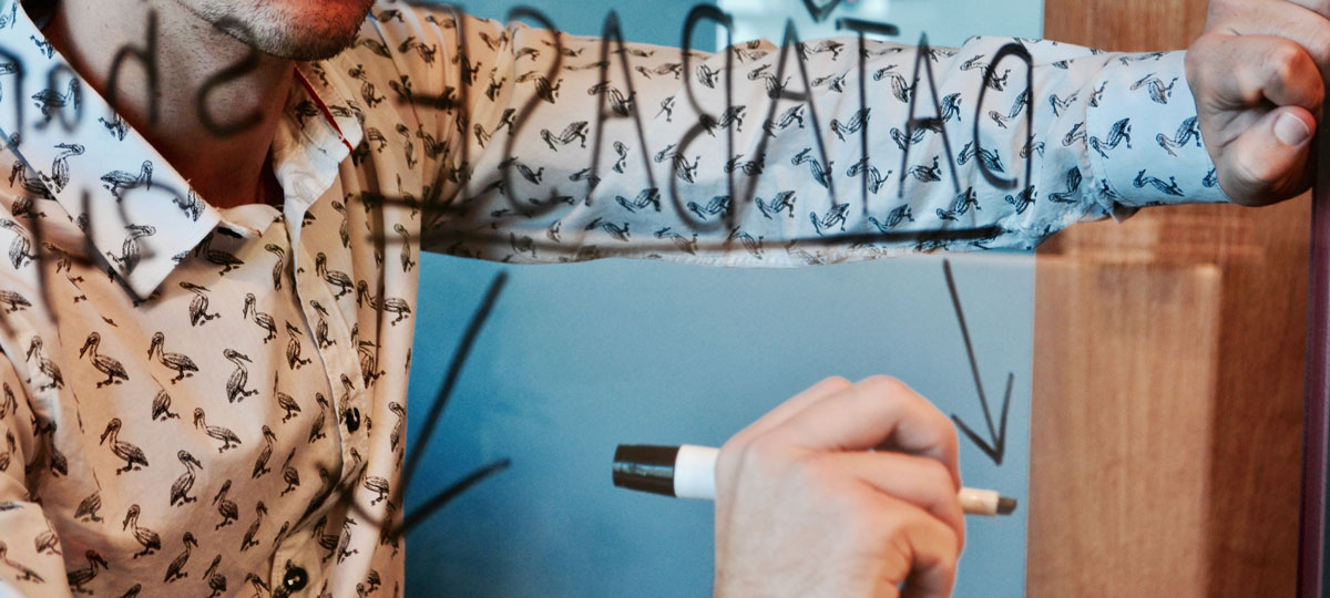 man writing on clear board making plans